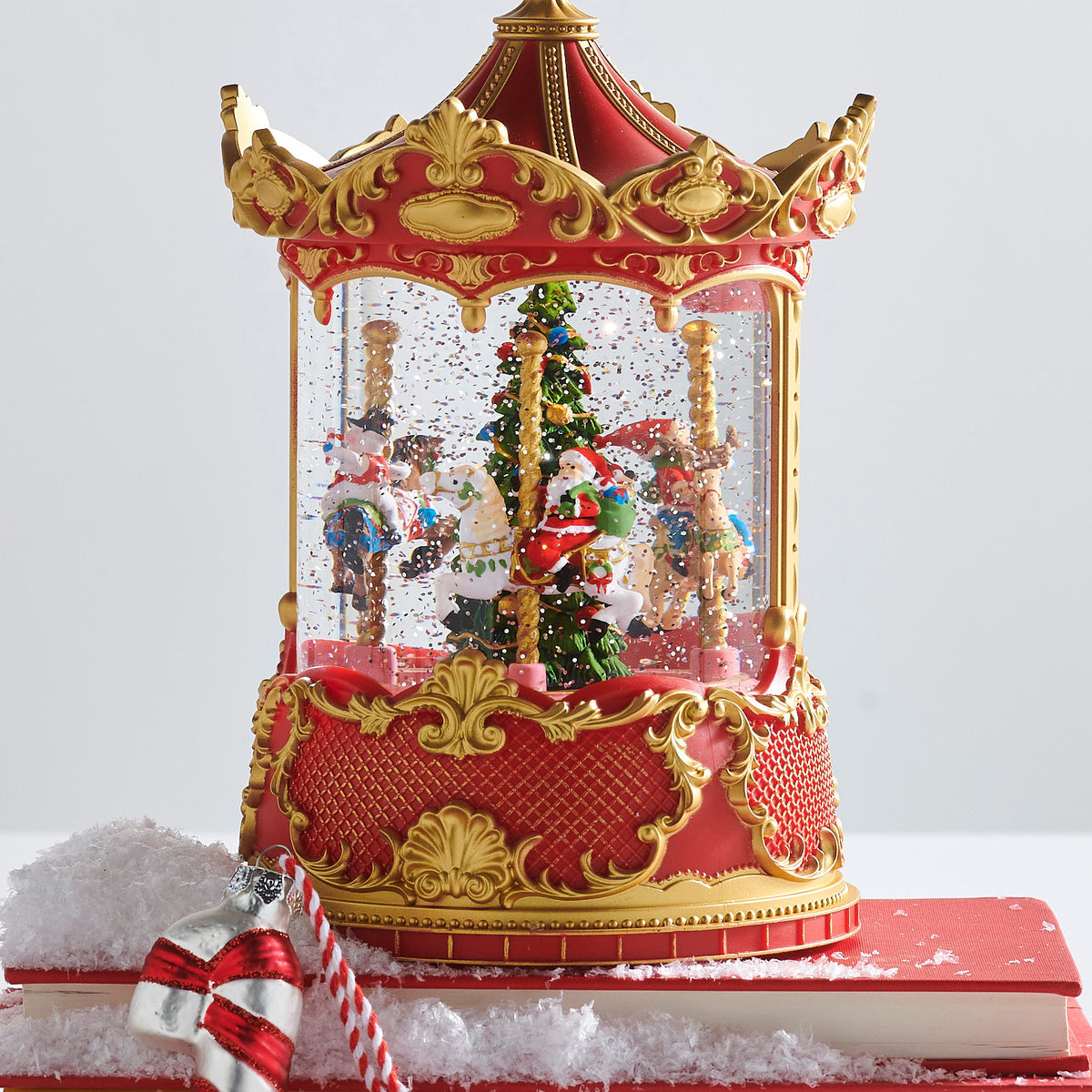 Decorative carousel snow globe with animated figures on a white background