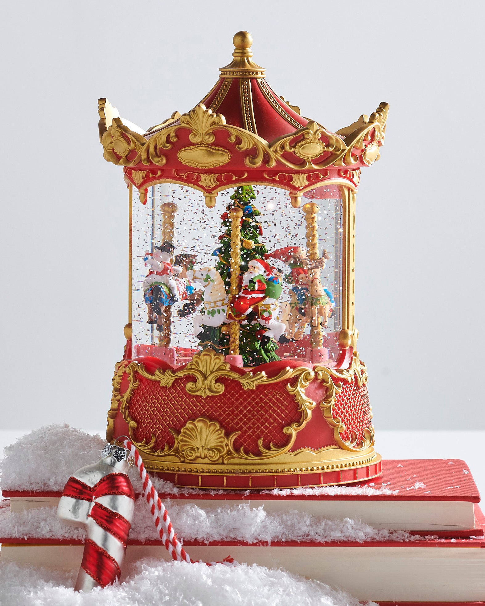 Decorative carousel snow globe with animated figures on a white background