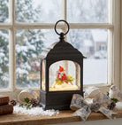black shaped lantern with cardinal snow globe on a window ledge with snowy day
