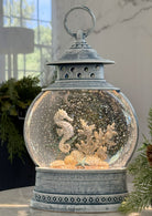 Decorative lantern with a snow globe containing seahorses and coral.