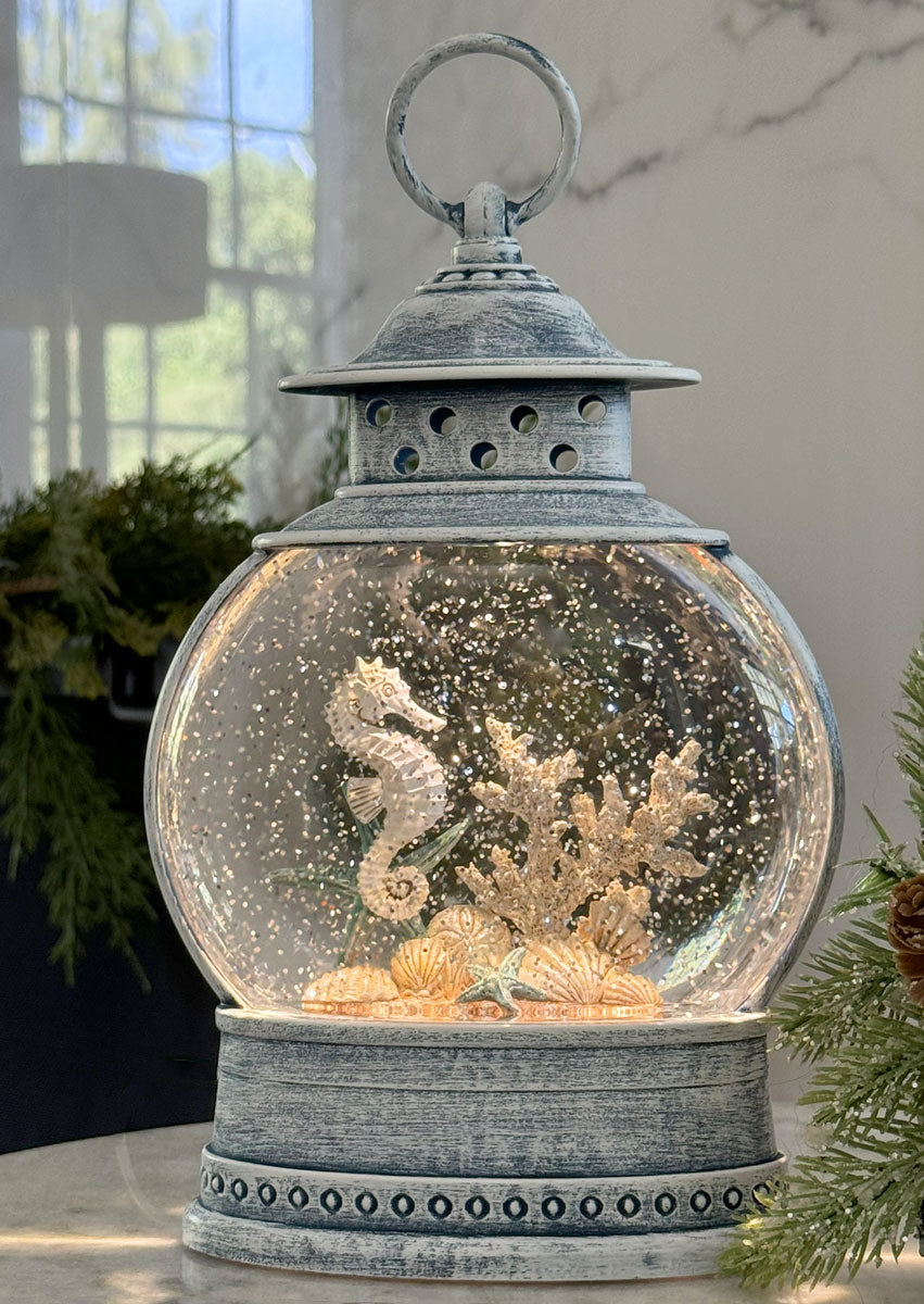Decorative lantern with a snow globe containing seahorses and coral.